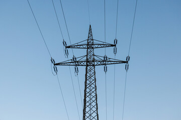 A large electrical transmission tower stands in a rural area with power lines extending into the distance, supporting energy distribution. © 24K-Production