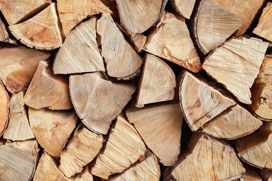 A close-up view of neatly stacked, split firewood showcasing the texture and grain of the wood pieces.