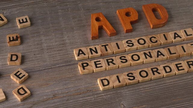 APD abbreviation on wooden letters and its individual words: Antisocial Personality Disorder, spelled out with wooden letter tiles on aged wooden boards. Camera slide.