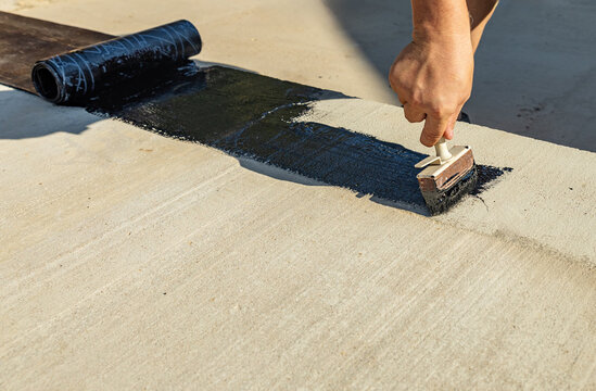 Construction techniques for waterproofing basement and foundations. Insulation material on the basement concrete wall. Waterproofing house foundation with spray on tar and roll waterproofing