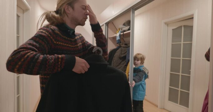 Man and kid boy take off warm clothes and put into wardrobe. Dad and son return home. 4K 10-bit