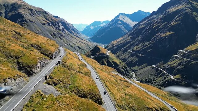 Aerial drone view of cars driving on winding mountain pass road in Alps