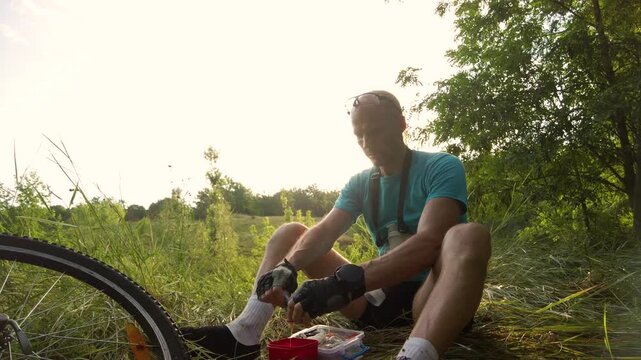 Male cyclist taking a break and eating snack during bicycle ride Cyclist sitting in nature taking food break during bike trip enjoying simple outdoor meal and rest