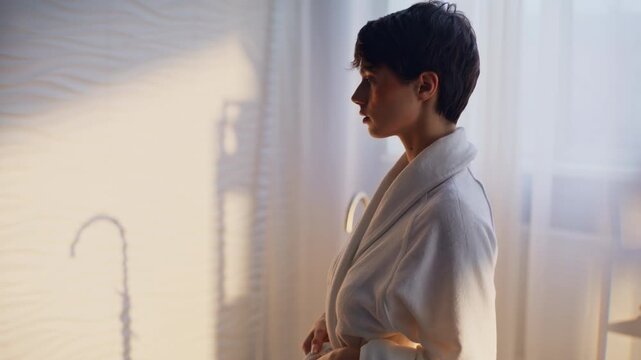 Woman removing terry robe revealing back closeup. Slim brunette lady spa session