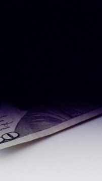 Lowlight partially hidden dollar under deep shadow, mystery scene clandestine envelope reveals bill edge, high contrast, tense noir mood, focus on texture and concealment
