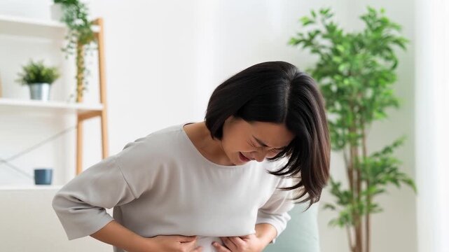 自宅で強い腹痛に耐える女性