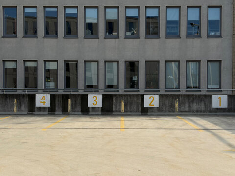 Facility Exterior Showing Unloading Docks With Painted Bay Numbers And Minimal Surroundings