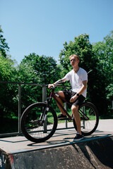 Obraz premium Young man performing tricks on a street bike in a skate park. Urban cycling, extreme sport and active outdoor lifestyle concept.