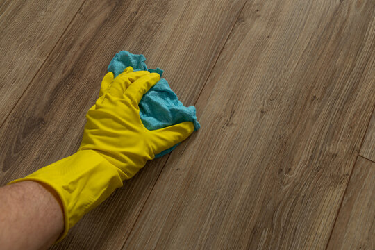 Dusting and mopping the floor in yellow rubber gloves, cleaning before the holidays, cleaning service professionally cleans the apartment,