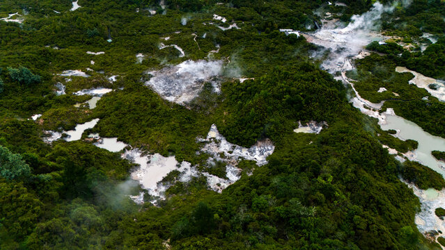 Aerial view of geothermal area with steam rising above mud pools and lush green vegetation, Rotorua, New Zealand.