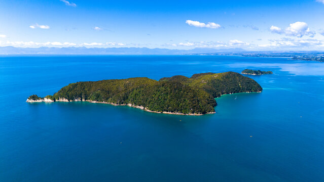 Aerial view of an island with lush green vegetation surrounded by the deep blue sea, Abel Tasman National Park, Tasman Region, New Zealand.