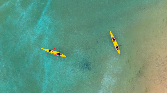 Aerial view of two yellow kayaks glide across the turquoise waters, their paddles creating ripples on the serene surface, Abel Tasman National Park, Tasman Region, New Zealand.