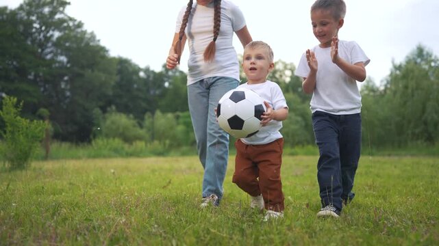 Three children playing with soccer ball. A boy is playing soccer outdoors. A girl and her siblings are having fun together in a casual activity. Three kids playing with a football lifestyle.