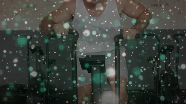 Animation of light spots over caucasian man exercising at gym