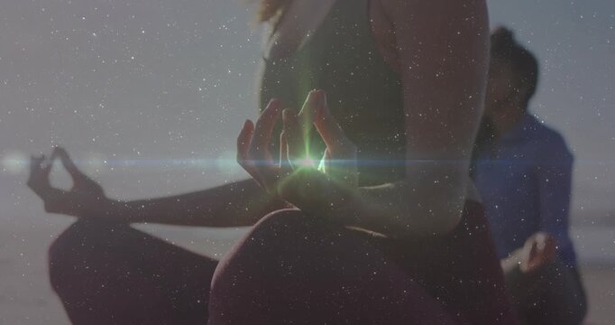 Foreground woman holding mudra at shore, sunlight causing flare sweeping to hands for wellness
