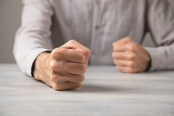 Fists of angry man beats on the table.