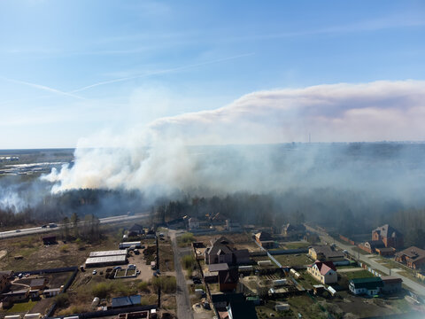 High-angle drone shot (top-down / bird's-eye view) of a forest fire (wildfire / bushfire) burning near suburban residential areas, captured using a DJI Mini 2. The image shows a massive plume of thick