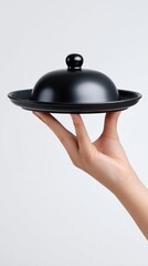 Elegant display of hand holding black serving platter with lid