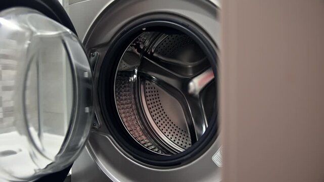 Opening washing machine door to reveal interior drum and washing space
