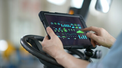Fototapeta premium Worker holding tablet to view industrial data charts and real-time monitoring interface