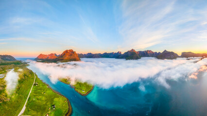 Aerial drone view of sunset over Lofoten mountains and fjords in Norway. Midnight sun landscape with arctic fog, moody clouds and scenic summer nature from above. © biletskiyevgeniy