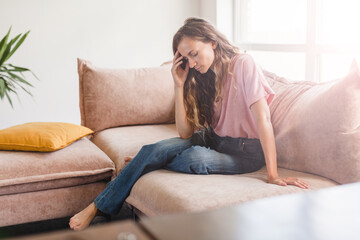 Obraz premium Sad woman thinking about problem, sitting alone on couch
