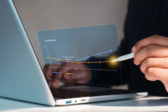 Business professional analyzing payback period and break even point on financial chart using stylus on laptop, revenue and cost comparison for ROI decision making in corporate finance analytics