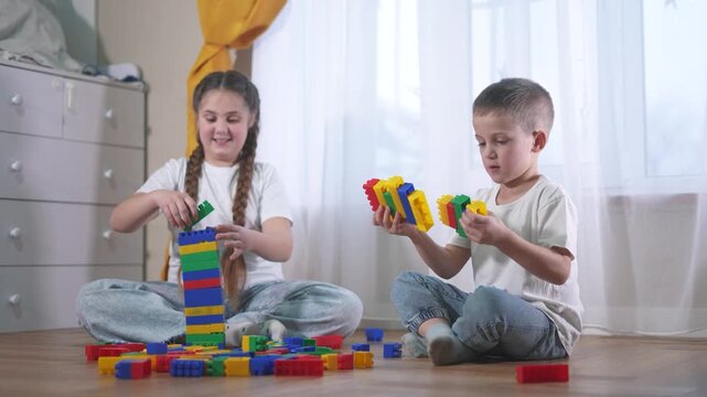 Two children playing with blocks. A group of children are assembling a construction. A group of kids play with toys. Two lifestyle kids stacking blocks.