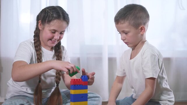 Two children playing with blocks. A group lifestyle of children are assembling a construction. A group of kids play with toys. Two kids stacking blocks.