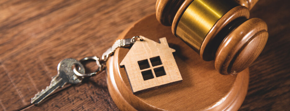 Judge gavel and house key on gray background