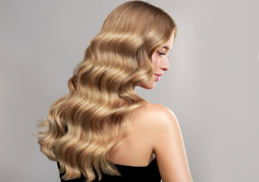 Beauty blonde girl with long and shiny wavy Hair ,coloring and toning, shatush , air touch and balayash . Beautiful woman model with curly hairstyle . Beauty salon and barbershop . Hair curling 
