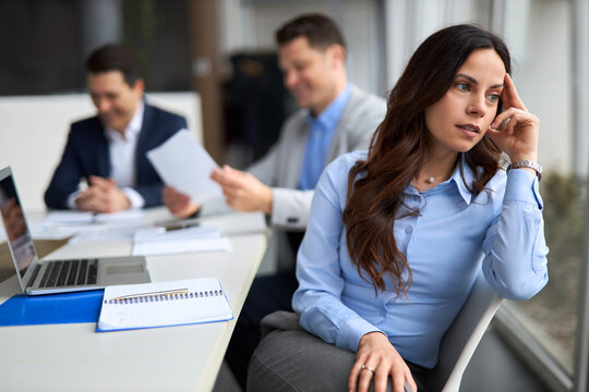 Displeased female entrepreneur having a meeting in the office. Her colleagues are in the background