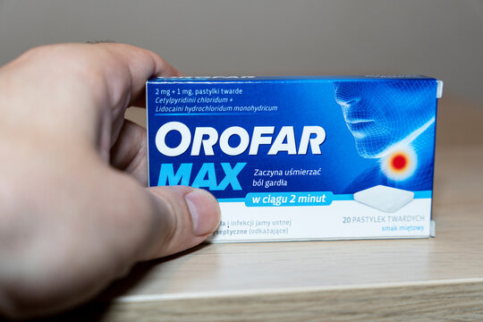 Warsaw, Poland - April 10, 2026: Hand holding an OROFAR MAX throat lozenge box. This box is designed to relieve throat pain with menthol flavor, highlighting healthcare benefits.