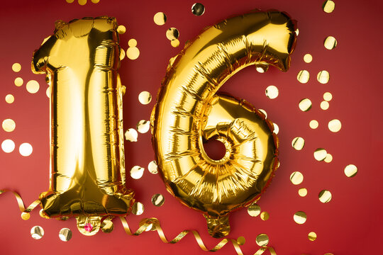 16th birthday celebration. Gold festive balloons number 16 year anniversary on red background with confetti. Birthday or wedding event.