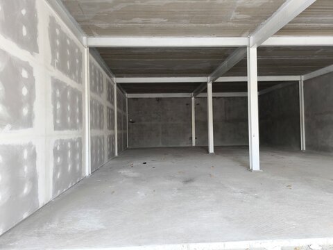 Empty concrete garage or storage unit under construction with steel frame. Industrial storage unit, a home garage under renovation, or a commercial warehouse shell