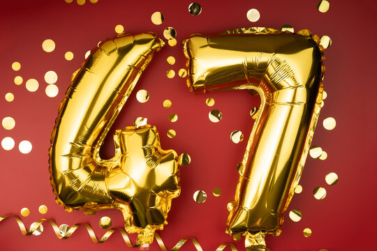 47th birthday celebration. Gold festive balloons number 47 year anniversary on red background with confetti. Birthday or wedding event.