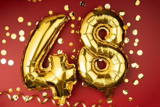 48th birthday celebration. Gold festive balloons number 48 year anniversary on red background with confetti. Birthday or wedding event.