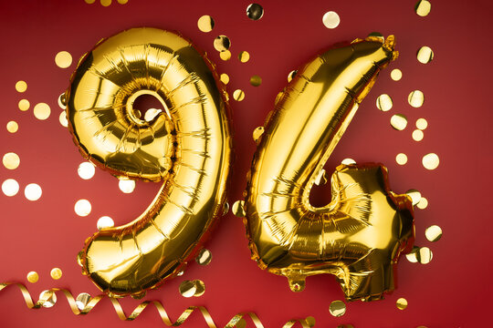 94th birthday celebration. Gold festive balloons number 94 year anniversary on red background with confetti. Birthday or wedding event.