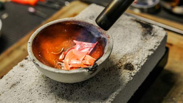 Artisan melting copper in a crucible with a propane torch