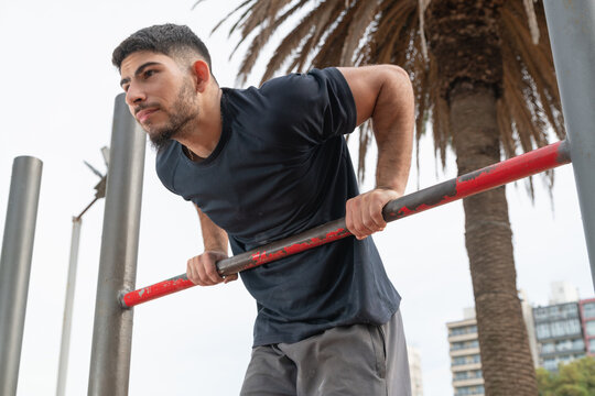 Man doing muscle up workout on parallel bars outdoors