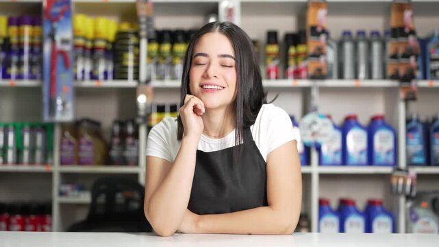 Young hispanic woman working at a hardware store smiling and posing behind the counter
