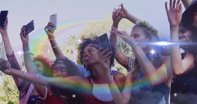 Front-row women raising smartphones to record concert, cheering with sparkles sweeping across crowd
