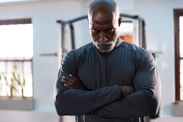 Senior African American man in dark athletic top, standing arms crossed, reflecting by power rack © wavebreak3