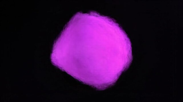 Abstract glowing purple amorphous shape floating and rotating in darkness