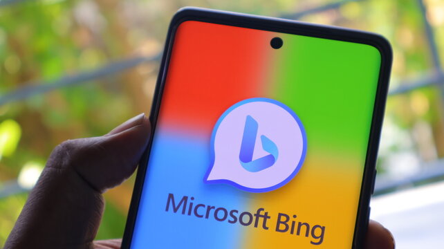 A hand holding a smartphone with the Microsoft Bing logo on the screen