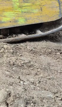Vertical side view of an industrial vibratory plate leveling soil, 9:16 aspect ratio