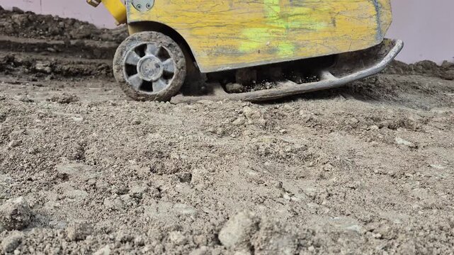 Side view of a vibratory plate compactor leveling the soil at a construction site.