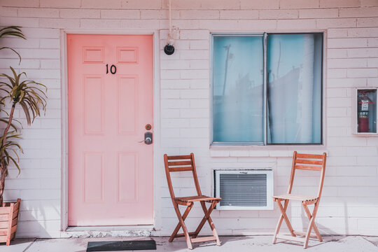 Pink motel room door with white brick walls, minimalistic retro mid-century modern style