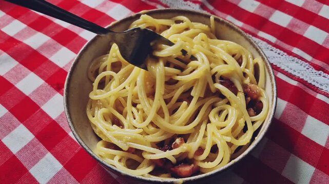 Slow motion mixing spaghetti carbonara in bowl with fork close up traditional pasta meal