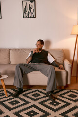Fototapeta premium Stylish young man relaxing on a couch in a cozy living room with modern decor